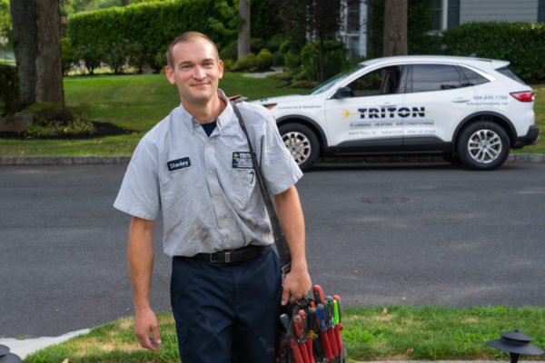 Triton plumbing and heating service technician approaching a home.