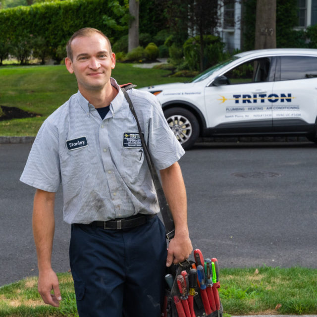 Triton plumbing and heating service technician approaching a home.